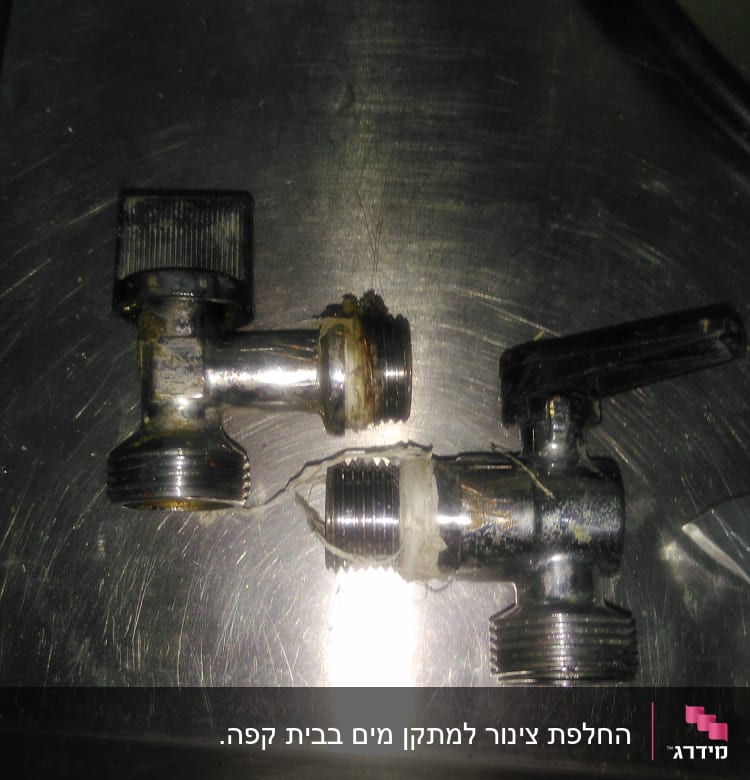 שני ברזים מתכתיים עם ידיות על משטח מתכת